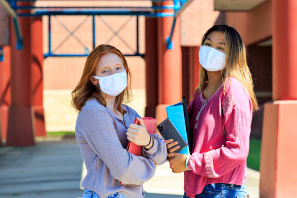 Female high school students attending school with face masks - fotografia de stock