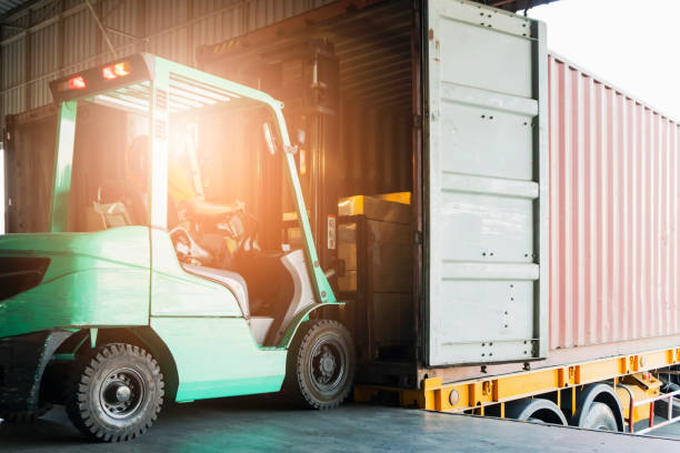 istock Forklift driver loading cargo pallet shipment goods into a truck container at dock warehouse. freight industry warehouse logistics transportation. 1256413810