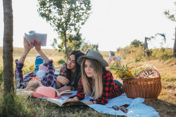 istock Young smiling women reading book on the picnic 1256420623