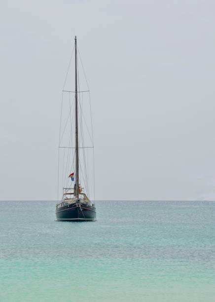 yacht seul au milieu d’une mer multicolore - sailing sailboat sunset aruba photos et images de collection