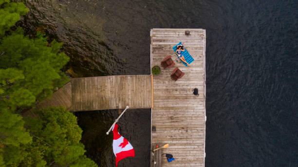 вид с воздуха на деревянный пирс в озере в мускоке с загаром молодой женщины - cottage life стоковые фото и изображения