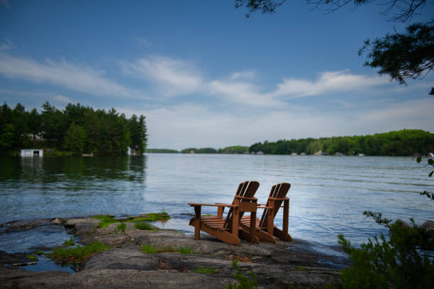 istock Adirondack chairs on a rock facing a lake 1256422206