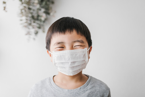 Portrait of Asian boy wearing white surgical mask.