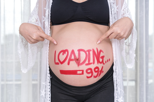 pregnant woman with loading 99% concept painted on her belly