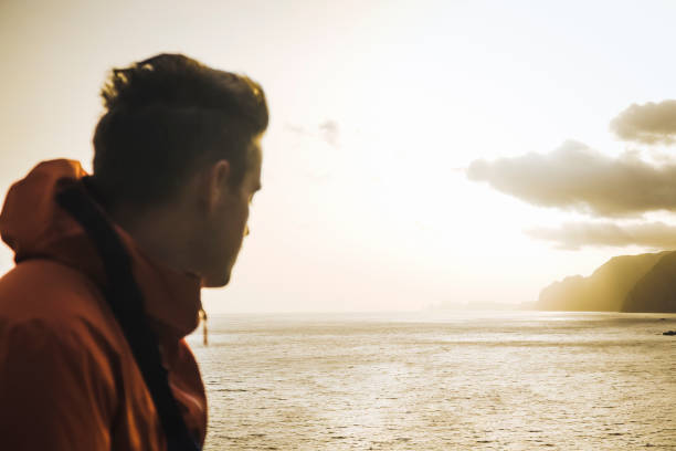istock Young man relaxes by waterfront at sunrise 1256426931