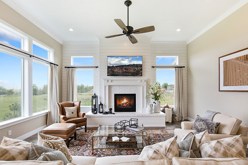 Ceiling fan hangs above gorgeous room with tall oversized windows