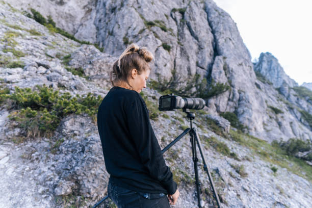 istock Young woman photographs distant mountain scene 1256428782
