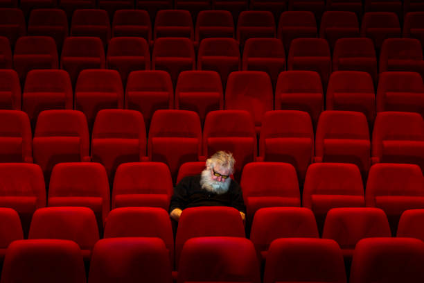 istock One man with white beard sits in Empty cinema or theatre with comfortable red seats, sleeping 1256431346