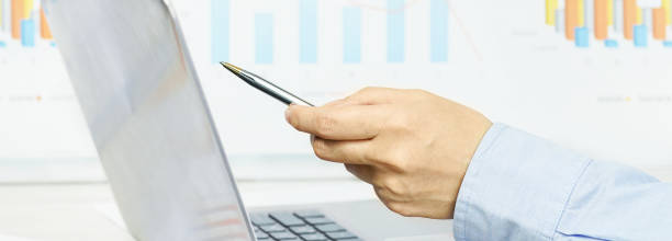 istock Finance. Female hand pointing at laptop screen financial graphs on desk 1256433878