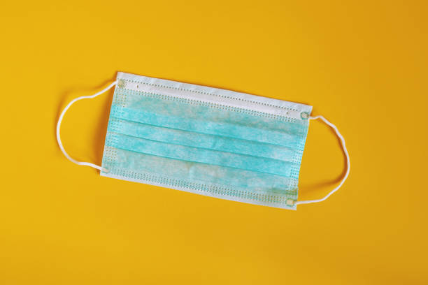 istock medical or surgical mask - protective face mask on yellow background 1256434520