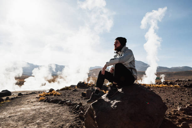 homme dans le champ géothermique d’el tatio dans les montagnes à atacama - geyser nature south america scenics photos et images de collection
