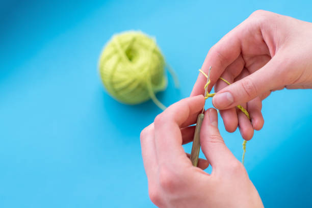 Crocheted hands with cotton and crochet on a light background, selective focus, with copy space, hobbies, leisure