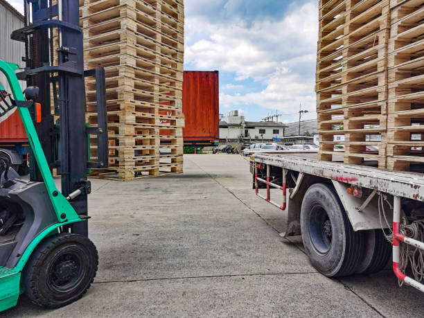 istock Worker driving forklift to loading and unloading wooden pallets from truck to warehouse cargo storage, shipment in logistics and transportation industrial, wood pallets stack 1256438075