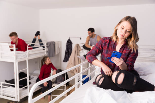 istock Young woman with phone on bed in hostel 1256438430