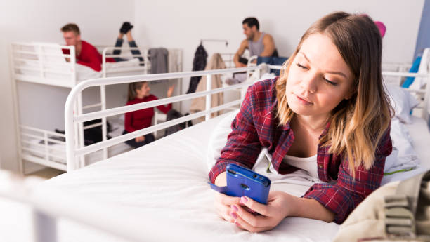 istock Woman with phone on bed in hostel 1256438432