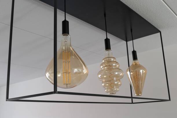 istock ceiling lamp made of black metal frame, holding 3 large sized decorative light bulb with a golden finish and spiral filament LED’s 1256444110