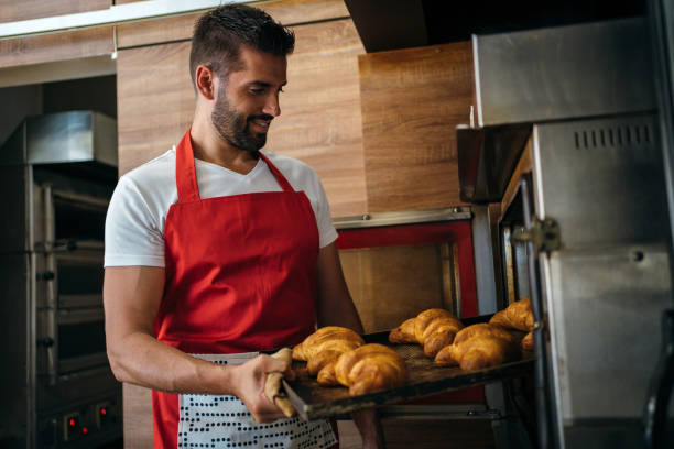 istock Baker taking fresh pastry out of the oven 1256444366