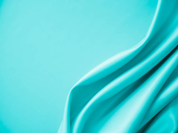 istock Beautiful elegant wavy turquoise silk or satin luxury cloth fabric texture, abstract background design. 1256447997