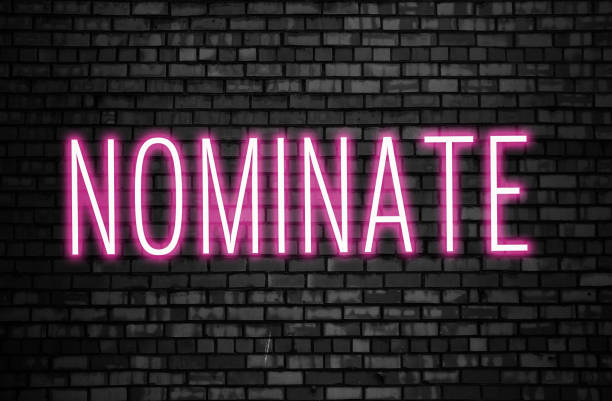 Nominate glowing pink neon sign on black brick wall. Business winner achievement concept for Election Nomination Nominate glowing pink neon sign on black brick wall. Business winner achievement concept for Election Nomination. nomination stock pictures, royalty-free photos & images