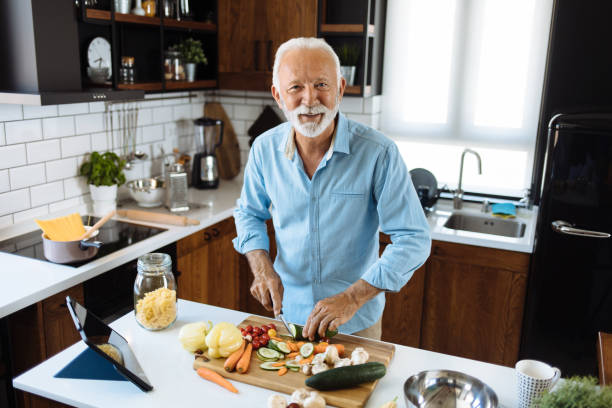 istock A handsome senior man watching a tablet while busy in the kitchen 1256448994