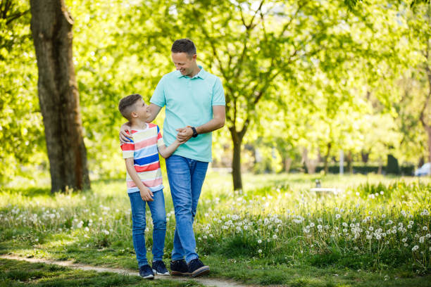 istock Father and son holding hands and walking through park 1256449054
