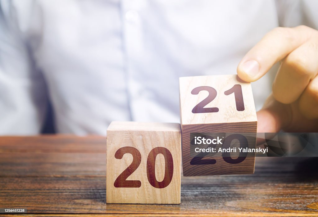 Hand flips a block changing 2020 to 2021. New year beginning. Holidays and Christmas. Trends and changes in the World. Build plans. New normal. Summing work done. Keep up with everything planned. 2021 Stock Photo