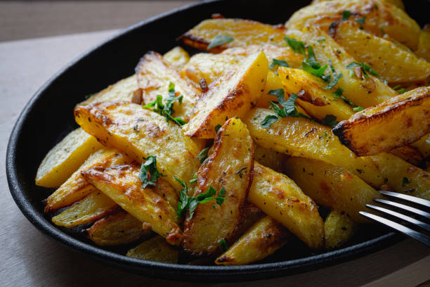 istock Fried potatoes in a rural style, with spices. On rustic pan, on a wooden table 1256454626