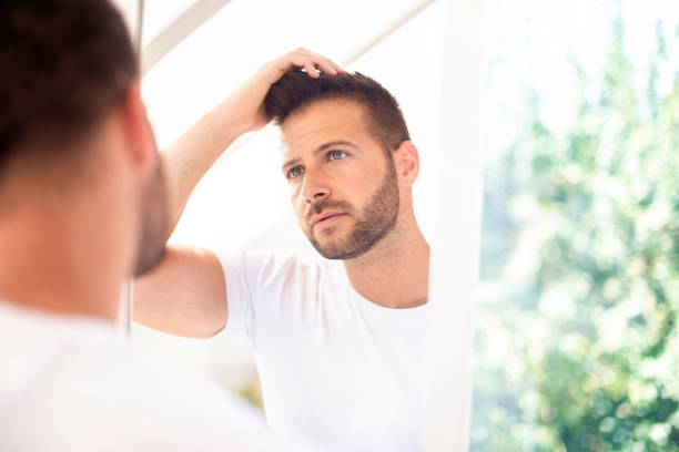 istock Handsome young man standing in front of bathroom mirror and looking his face 1256456307