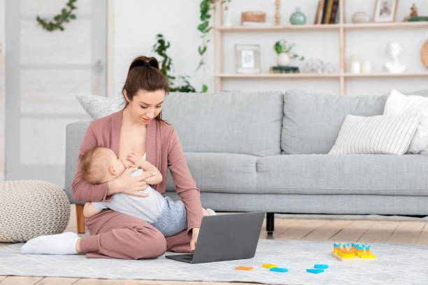 istock Young Mom Breastfeeding Baby While Working On Laptop At Home 1256459511