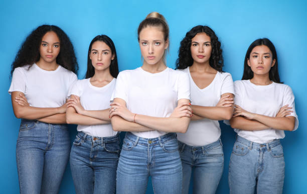 istock Discontented Girls Posing Crossing Hands Looking At Camera In Studio 1256460539