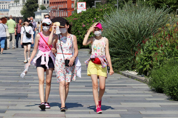 trois filles dans des masques protecteurs marchant sur une rue d’été - heating element photos et images de collection