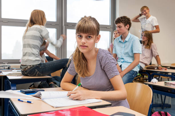 istock sad high school girl in chaotic classroom 1256462039