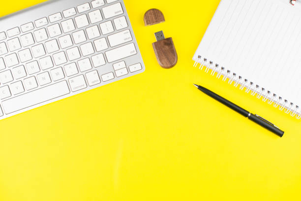 istock Keyboard, black pen, notepad planner and wooden USB flash on yellow background. Flat lay. Copy space. Workplace in the office. 1256462138