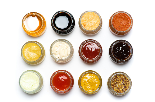 Large collection of sauces and spiced spreads in small jars isolated flat lay tabletop
