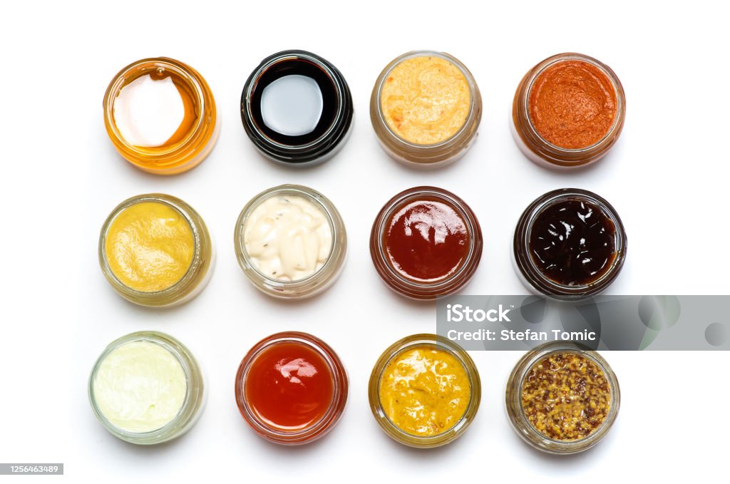 Large collection of sauces and spiced spreads in small jars isolated flat lay Large collection of sauces and spiced spreads in small jars isolated flat lay tabletop Dipping Sauce Stock Photo