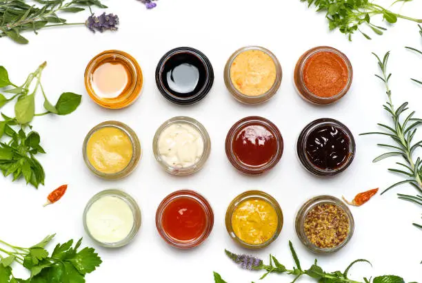 Photo of Large collection of sauces and spiced spreads in small jars isolated flat lay