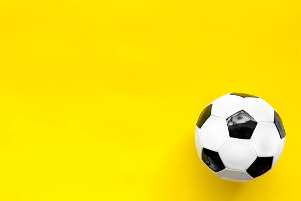 istock Soccer ball on yellow background top view copy space 1256464438