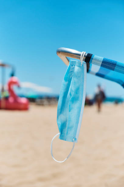 istock surgical mask hanging on a deck chair on the beach 1256464917