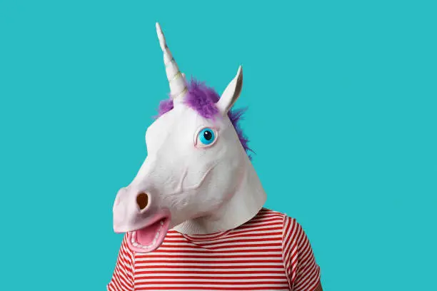 man wearing a unicorn mask and a red and white striped t-shirt on a blue background with some blank space around him