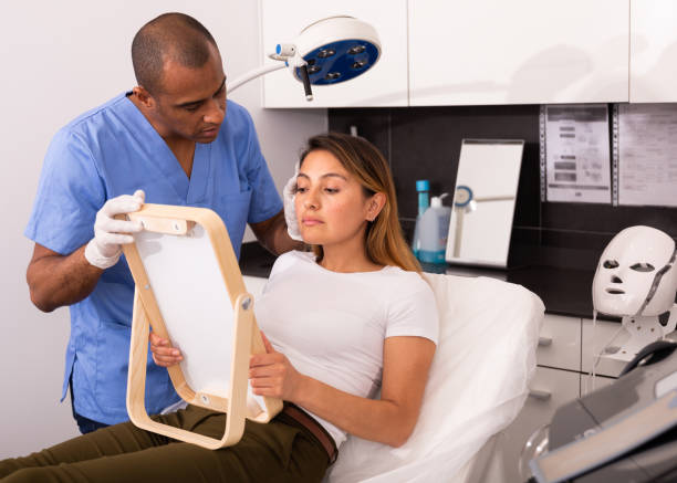 istock Cosmetologist examining female client face before procedure 1256466239