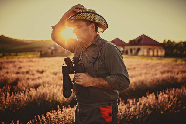 istock Mature male farmer with binoculars in lavender field 1256467158