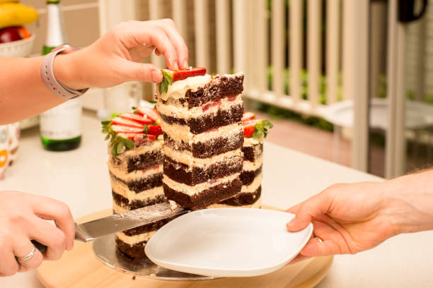 istock Delicious handmade double barrel tall layered cake decorated with strawberries on a cake stand. Cutted slice being served 1256471161