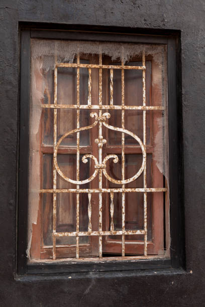 istock Picturesque old window with rusty wrought iron bars. 1256471778