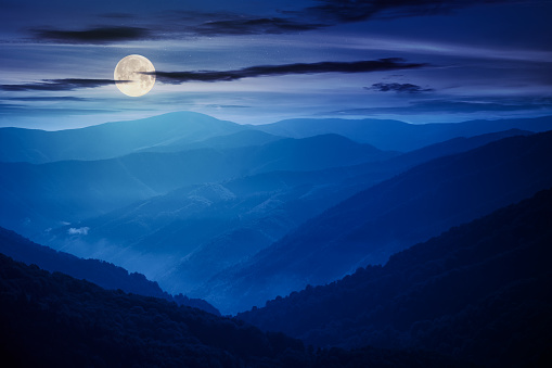 mountain landscape on a summer night. hills rolling from the valley up in to the distant ridge. view of the summer scenery in full moon light