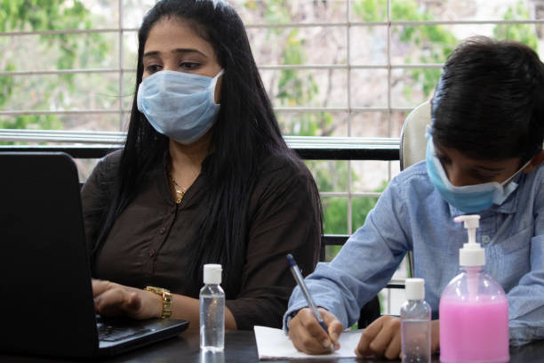 istock Mother working on laptop and upbringing son studying at home 1256474256