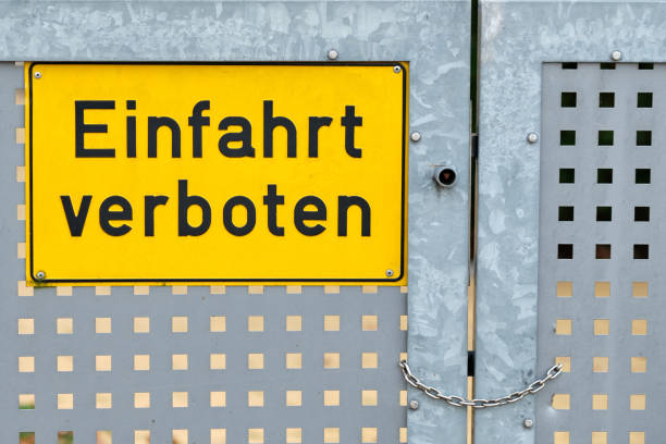 istock Yellow sign on iron gate says driveway banned 1256475654