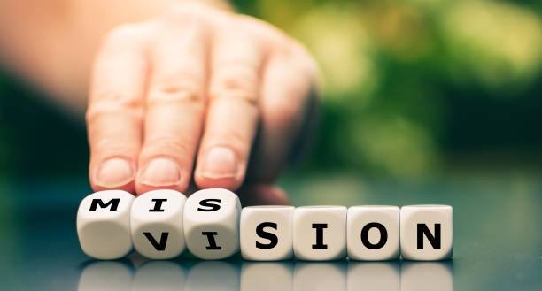 From a vision to a mission. Hand turns dice and changes the word vision to mission. stock photo