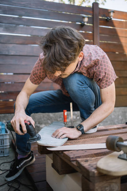 istock Young man using sander and polishing wooden board 1256476709