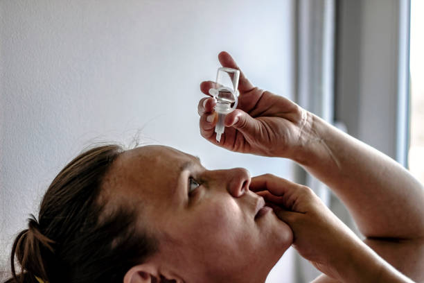 istock Young female using bottle of eye liquid 1256476910
