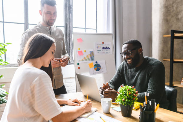 istock Young multiracial coworkers working out business strategy together and discuss tasks while sitting at the office desk. Team work 1256477152